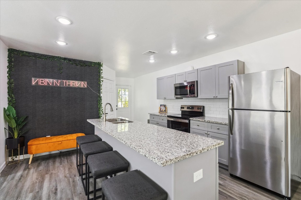 2631 Stevens Street Houston, TX 77026 - Photo 6 of 25 a kitchen with stainless steel appliances granite countertop a refrigerator a stove and a sink with wooden floor