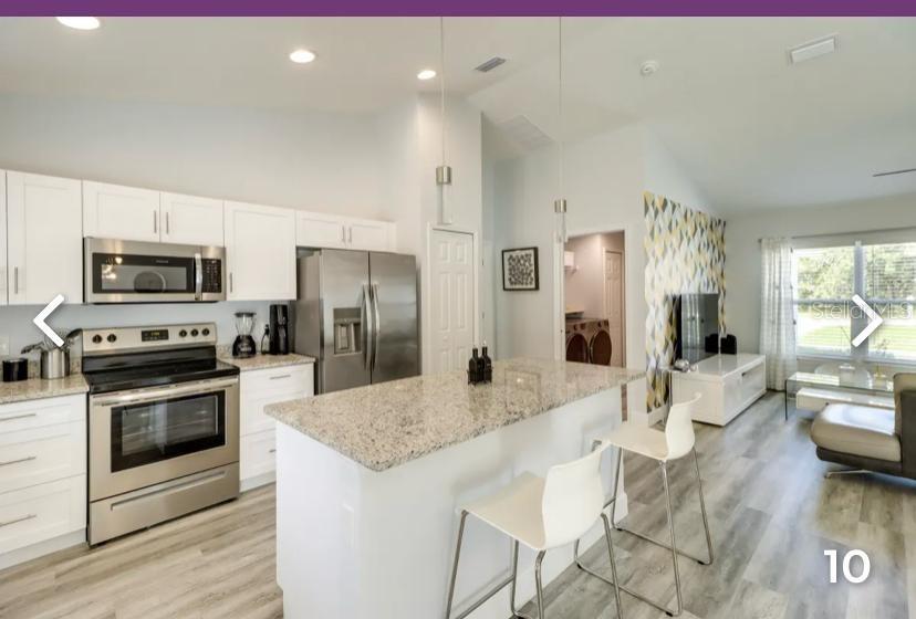 2081 Southwest 153rd Loop Ocala, FL 34473 - Photo 7 of 20 a large kitchen with granite countertop a stove a sink a refrigerator and a dining table with wooden floor