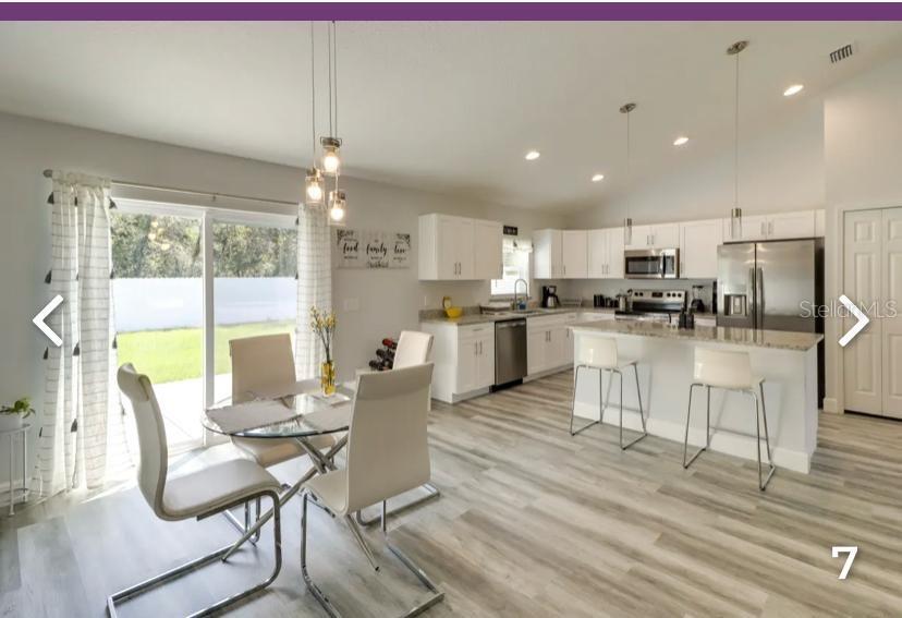 2081 Southwest 153rd Loop Ocala, FL 34473 - Photo 10 of 20 a kitchen with kitchen island granite countertop a dining table chairs refrigerator and cabinets