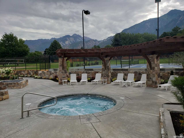 3 Carriagewood Cove, Unit 1088 Sandy, UT 84092 - Photo 71 of 79 Outdoor spa featuring concrete decking, a stone-clad pergola, and integrated landscaping with mature plantings