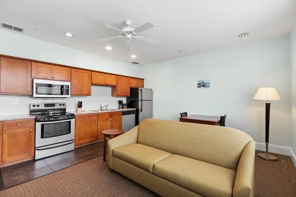 a living room with stainless steel appliances furniture and a kitchen view