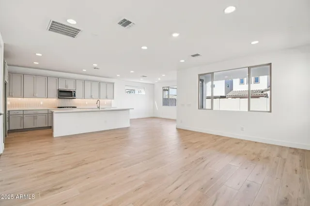a large white kitchen with kitchen island a sink wooden floor and a refrigerator