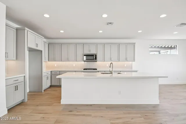 a large kitchen with stainless steel appliances a large counter top a stove a refrigerator cabinets and a center island