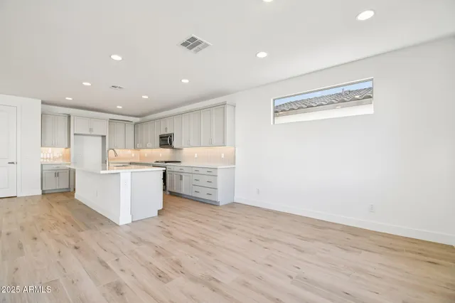a large white kitchen with a refrigerator a counter top space and cabinets