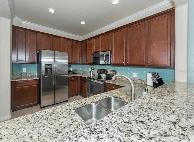 a kitchen with stainless steel appliances granite countertop a refrigerator sink and stove