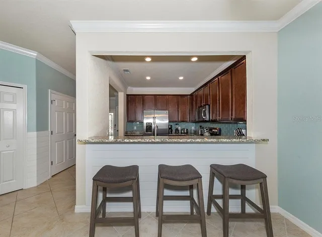 a kitchen with stainless steel appliances granite countertop a table chairs sink and cabinets