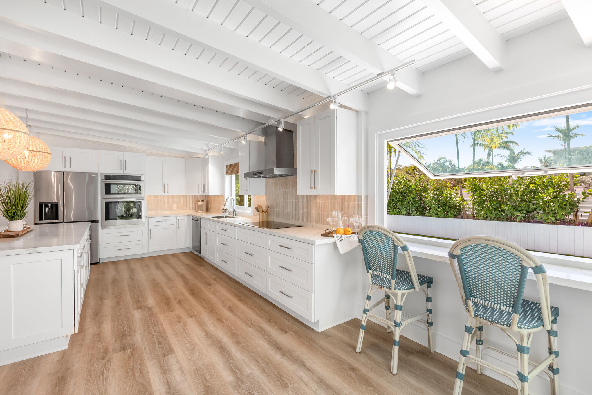 1701 Atlantic Boulevard Key West, FL 33040 - Photo 15 of 39 a large white kitchen with cabinets a island a stove a dining table and chairs with the wooden floor