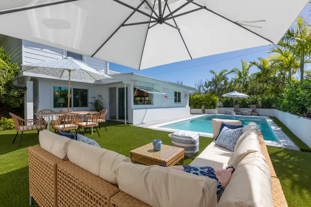 a view of a patio with couches table and chairs under an umbrella