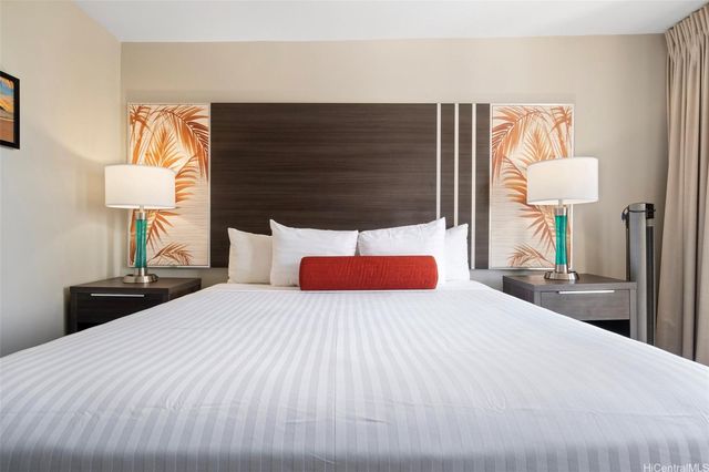 a bedroom with a bed and a lamp on dresser