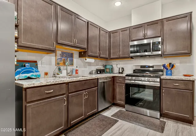 a kitchen with stainless steel appliances granite countertop a sink a stove and a microwave