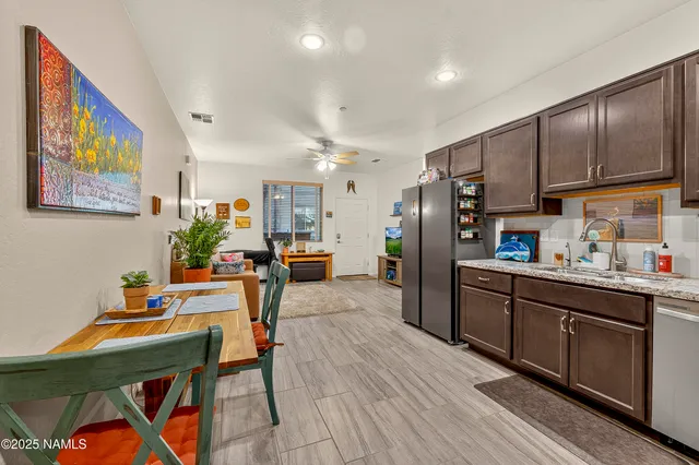 a kitchen with stainless steel appliances kitchen island granite countertop a refrigerator a stove a sink dishwasher and a dining table with wooden floor