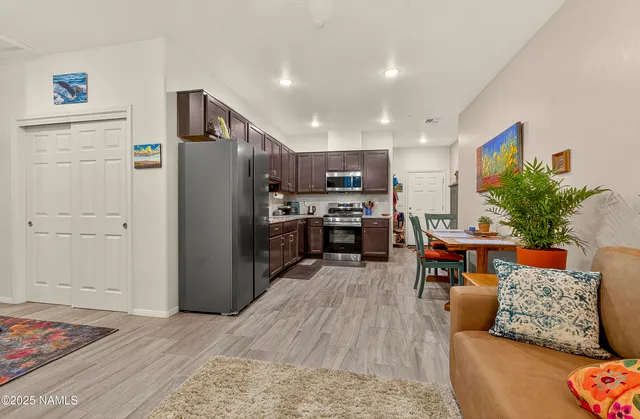 a living room with stainless steel appliances furniture wooden floor and a view of kitchen