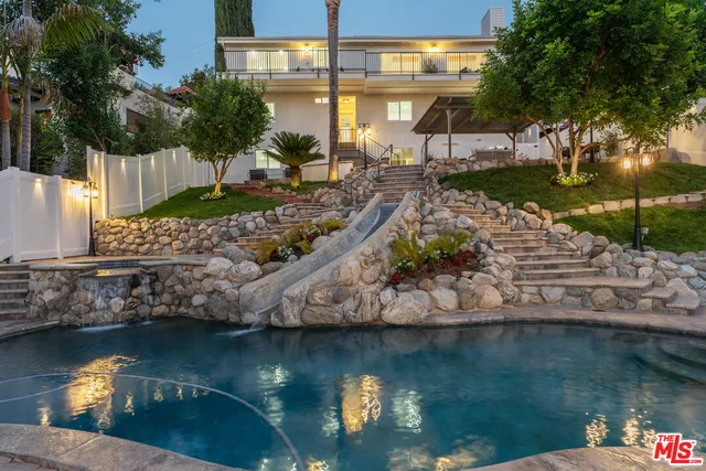 a view of a backyard with a fountain and a large tree
