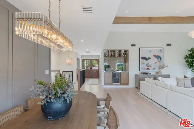 a living room with furniture potted plant and kitchen view
