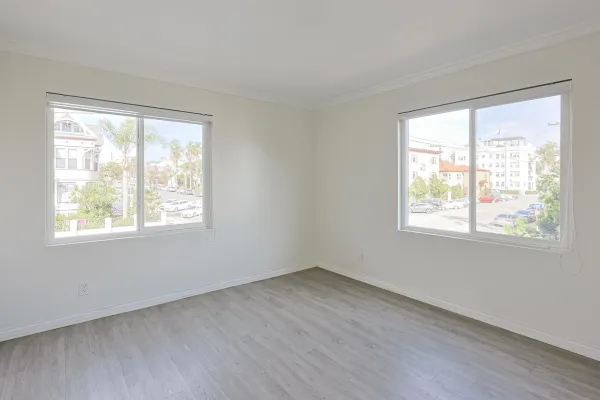 a view of an empty room with wooden floor and a window