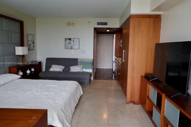 a bedroom with a bed and a flat tv screen on a dresser