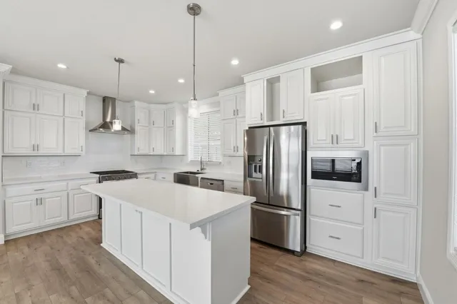 a kitchen with a refrigerator a sink and white cabinets