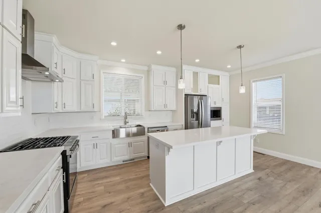 a large kitchen with stainless steel appliances granite countertop a sink a stove and a refrigerator