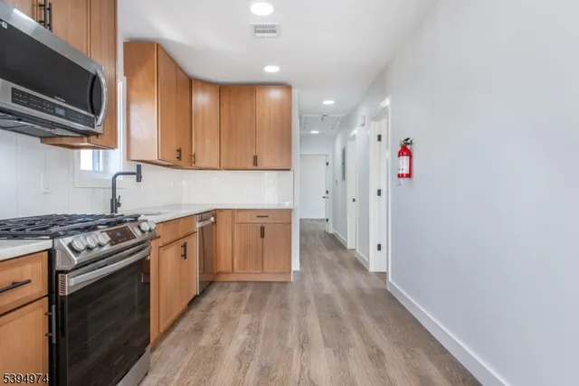 a kitchen with granite countertop a stove top oven a sink dishwasher cabinets and wooden floor