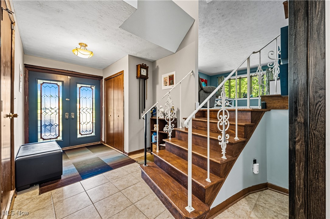 8193 Hartman Road Wadsworth, OH 44281 - Photo 3 of 50 Foyer with a textured ceiling, light tile patterned floors, french doors, and stairway