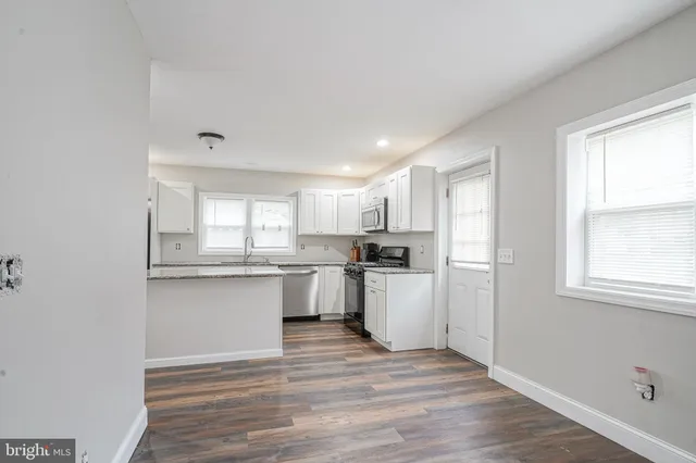 a kitchen with a white cabinets wooden floor and a sink