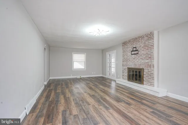wooden floor fireplace and windows in an empty room