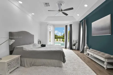 a bedroom with a bed ceiling fan and a large window