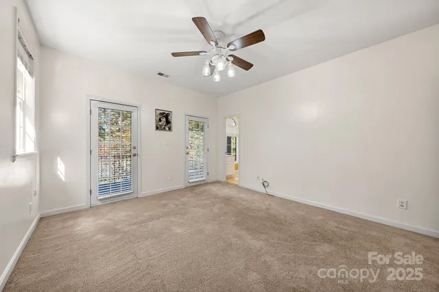a view of an empty room with a chandelier fan