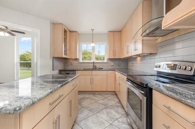 a kitchen with granite countertop a sink a stove and cabinets