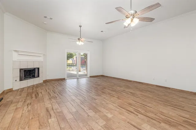 an empty room with wooden floor fireplace and windows