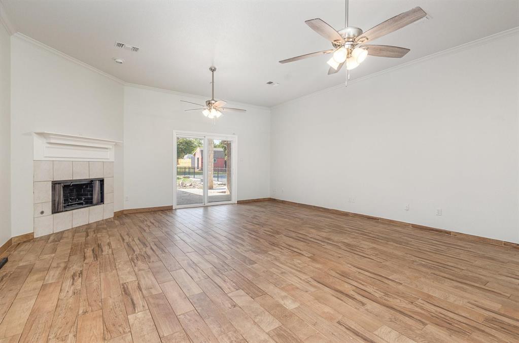 3961 Joe Wilson Road Midlothian, TX 76065 - Photo 8 of 27 an empty room with wooden floor fireplace and windows