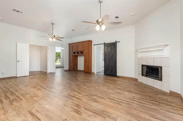 a view of a livingroom with a fireplace a ceiling fan and kitchen view