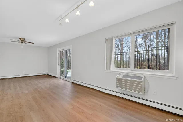 a view of an empty room with a window and wooden floor