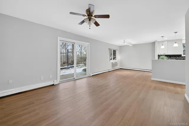 a view of an empty room with a window and wooden floor