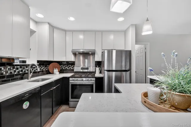 a kitchen with stainless steel appliances kitchen island granite countertop a refrigerator a sink a stove and cabinets