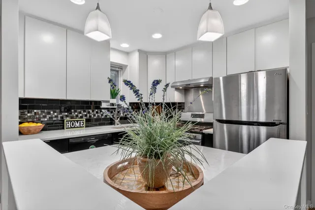 a kitchen with stainless steel appliances granite countertop a refrigerator a sink a stove and a dining table