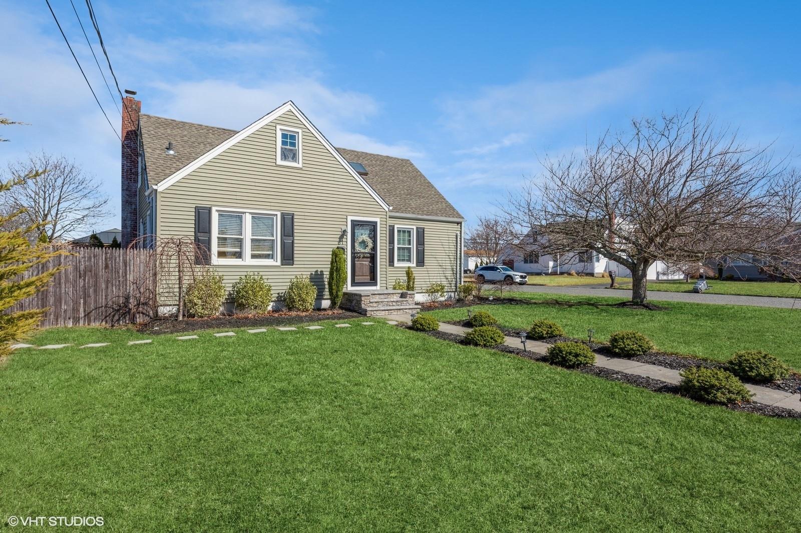 View of front facade with a front lawn, fence, roof with shingles, and a chimney