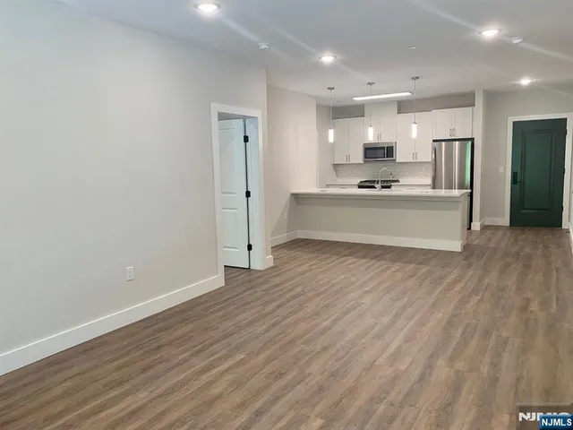 a view of large kitchen with wooden floor and stainless steel appliances