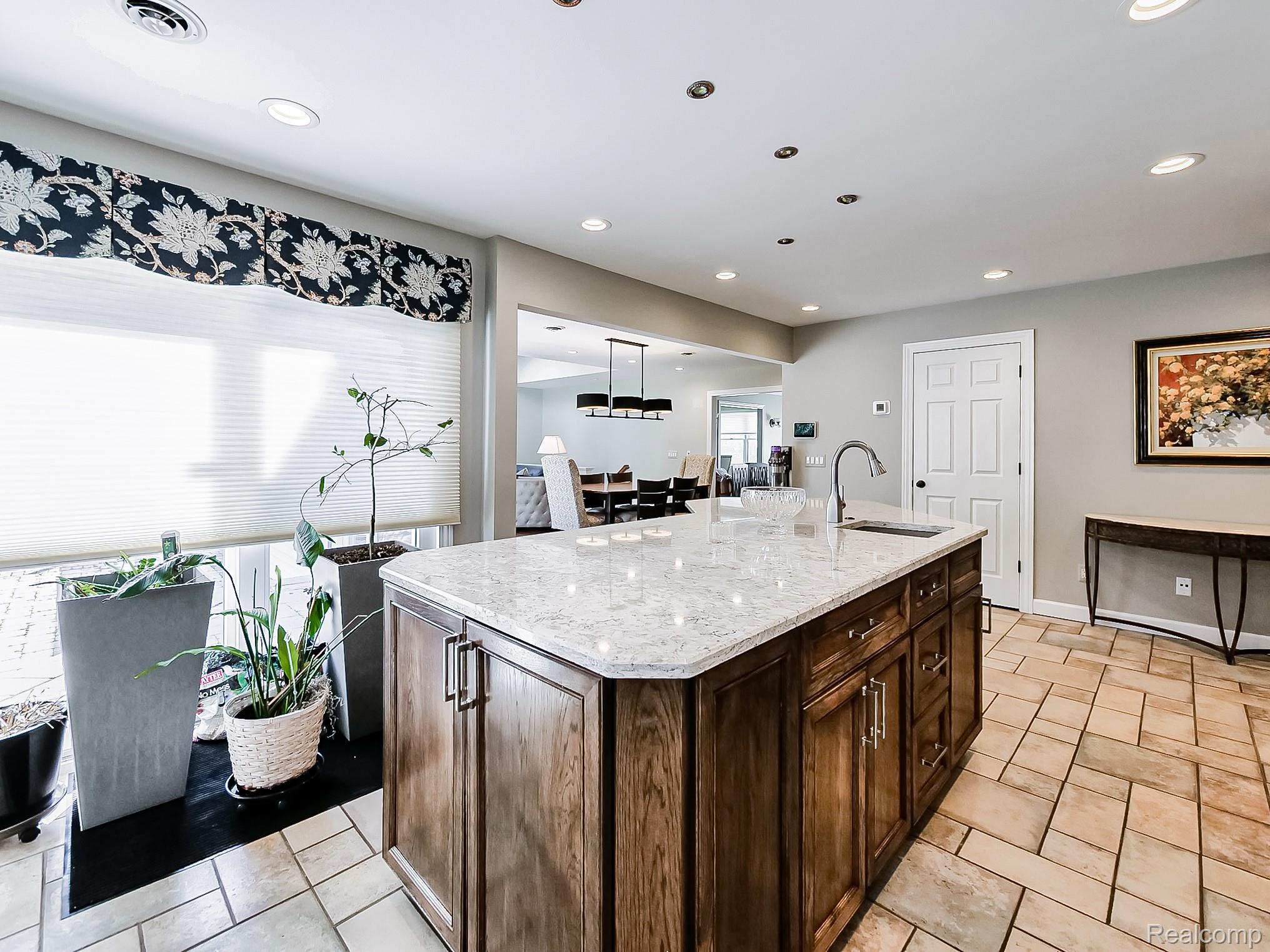 3720 East Clarkston Road Oakland, MI 48363 - Photo 57 of 60 Kitchen featuring a kitchen island with sink, dark wood finish cabinetry, light stone counters, hanging light fixtures, and open floor plan