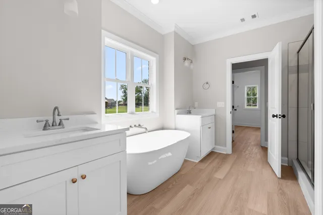 a spacious bathroom with a double vanity sink a mirror and a bathtub