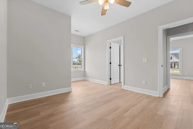 a view of an empty room with chandelier fan and fire place