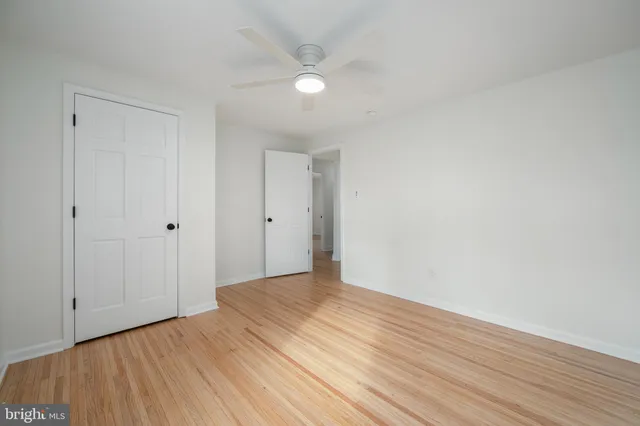 an empty room with wooden floor ceiling fan and windows