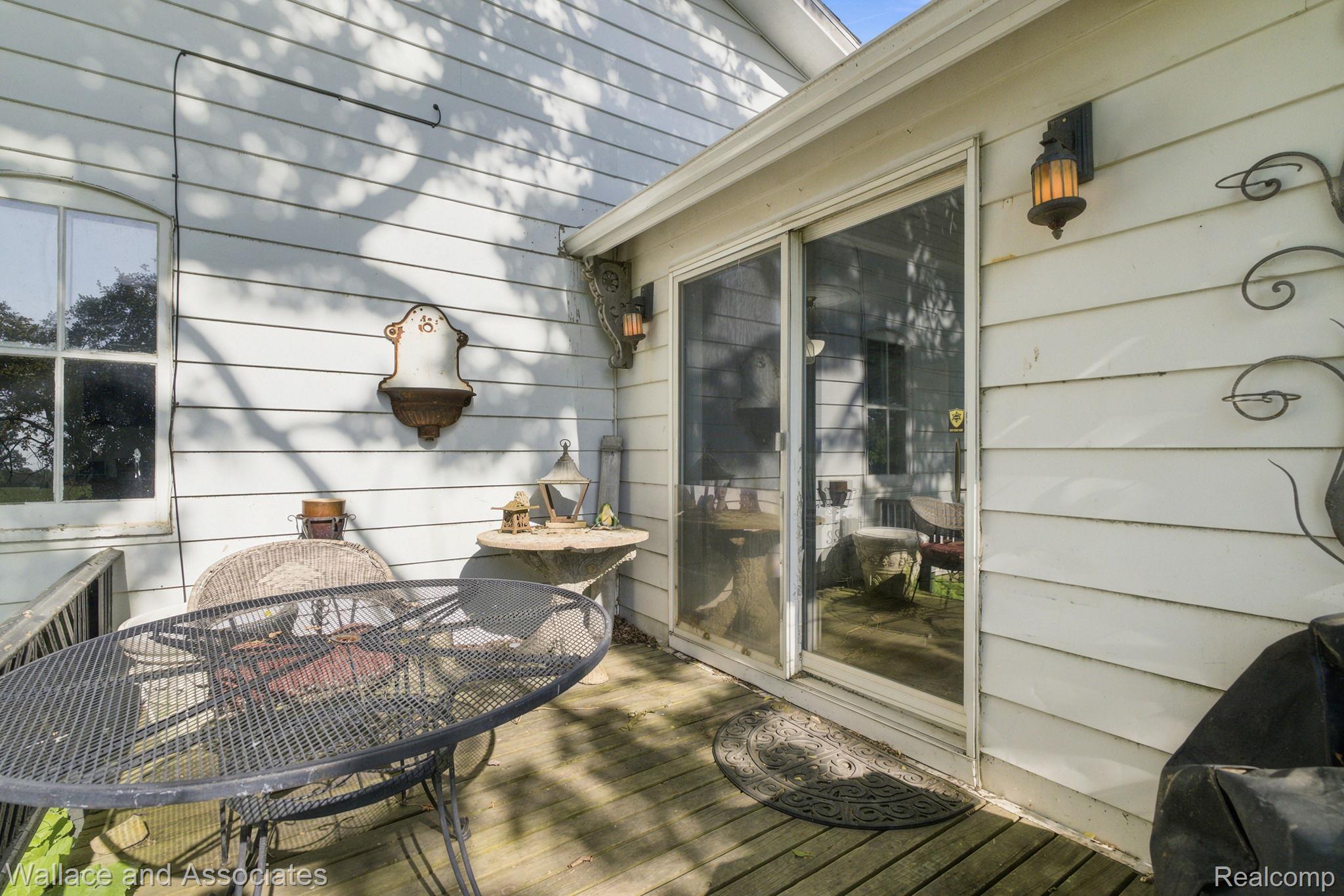 5949 Roach Road Croswell, MI 48422 - Photo 9 of 48 Wood deck with white siding exterior featuring an arched window, decorative wall sconces, and a sliding glass door