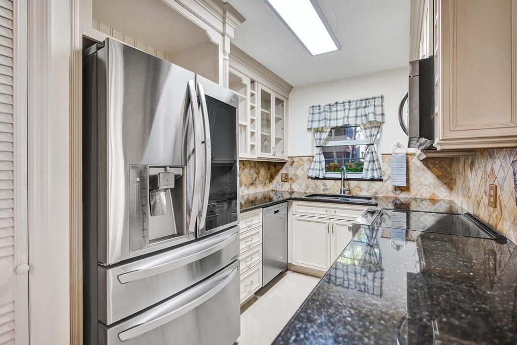 a kitchen with granite countertop stainless steel appliances a refrigerator stove top oven and sink