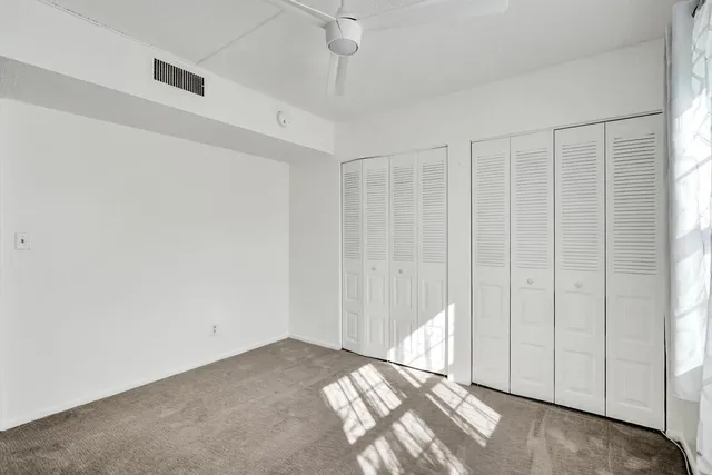 a view of a big room with windows and ceiling fan