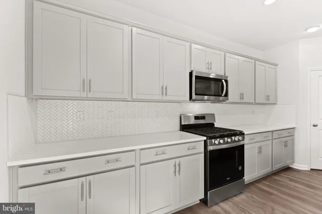 a kitchen with white cabinets and black appliances
