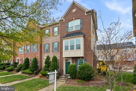 a front view of a multi story residential apartment building with yard and green space