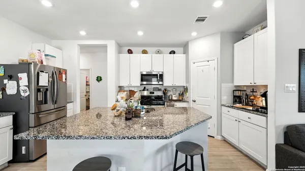a kitchen with stainless steel appliances granite countertop a sink refrigerator and cabinets