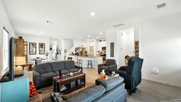 a living room with furniture and a dining table with wooden floor