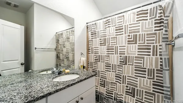 a bathroom with a granite countertop sink and a shower